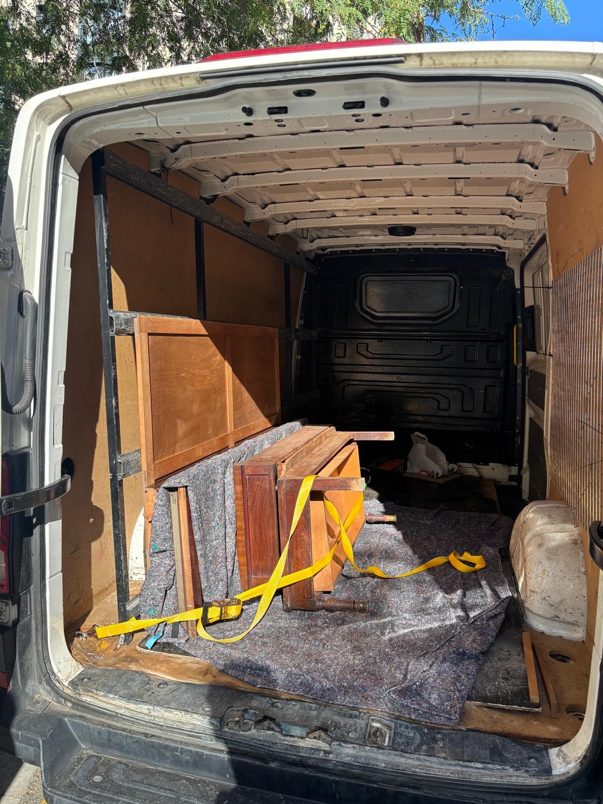 Wooden furniture picked up and protected with a blanket and strap in Campsil's van