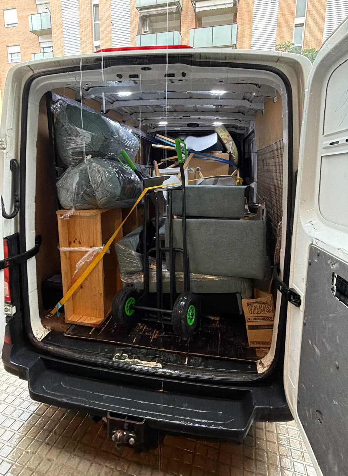 Furgoneta de Campsil cargada con un sofá protegido y muebles sujetos con correas, lista para un porte en Barcelona